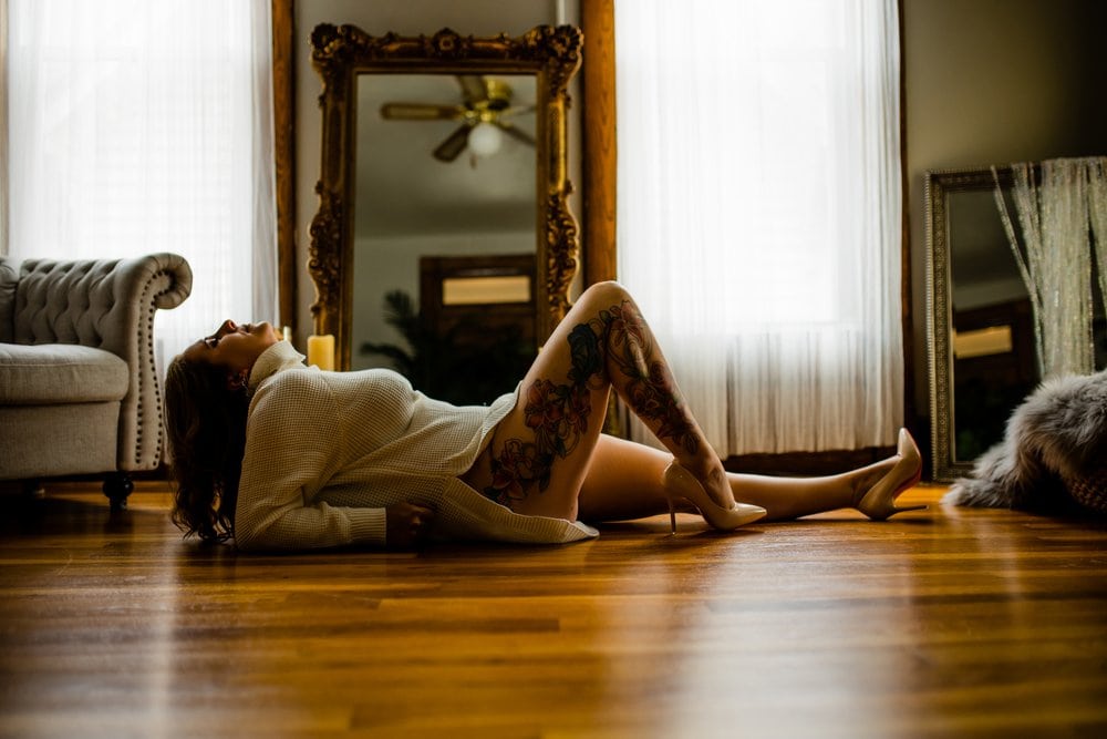 A woman laying on the floor in front of a mirror for a photoshoot.