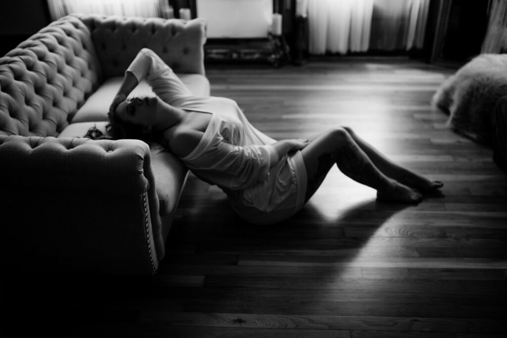 A woman laying on the floor in front of a couch.