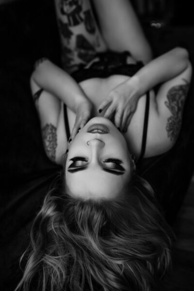 Boudoir Gallery showcasing a black and white photo of a woman with tattoos on a bed.