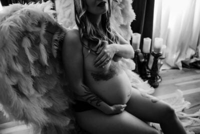 A pregnant woman in a black and white photo with angel wings.