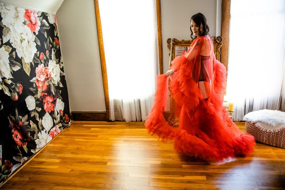 A woman in a red dress standing in a room for a photoshoot.