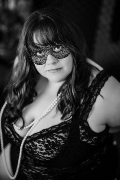 A black and white photo of a woman wearing a mask, perfect for boudoir photography.