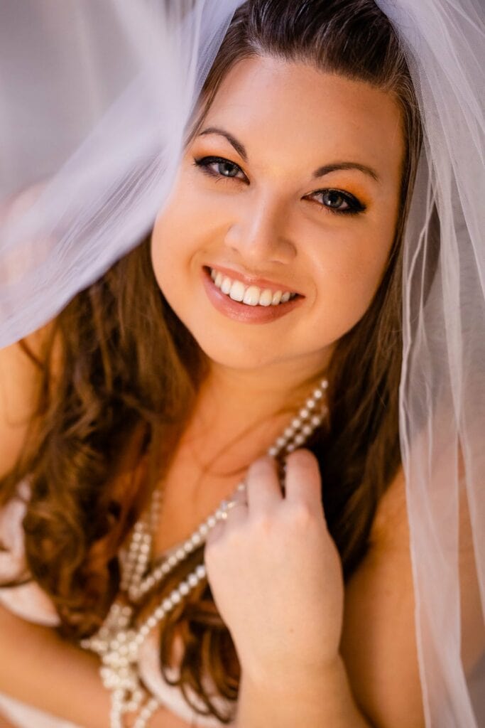 A bride wearing a veil and pearls elevates your boudoir photography session.