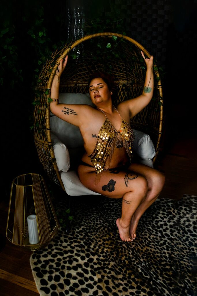 A woman sitting in a rattan chair during a photoshoot.