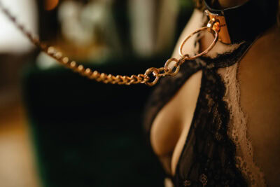 A woman in a black lingerie with a chain around her neck.