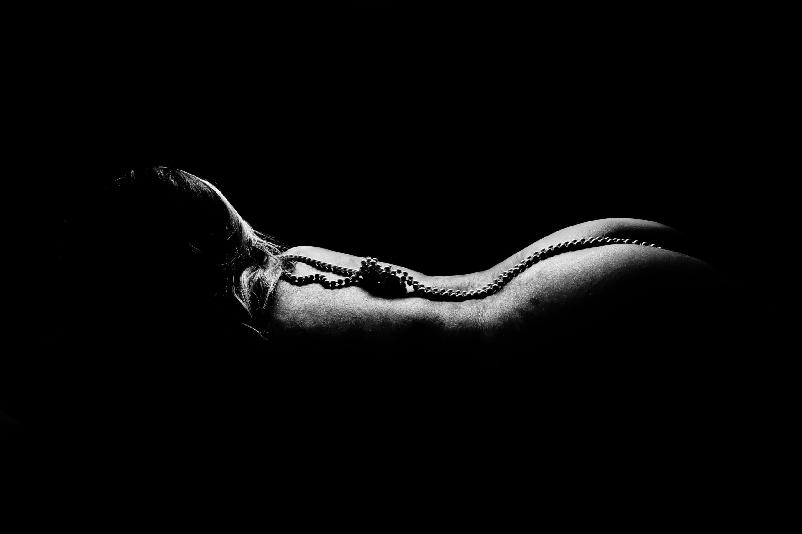 A black and white photo of a woman laying in the dark.