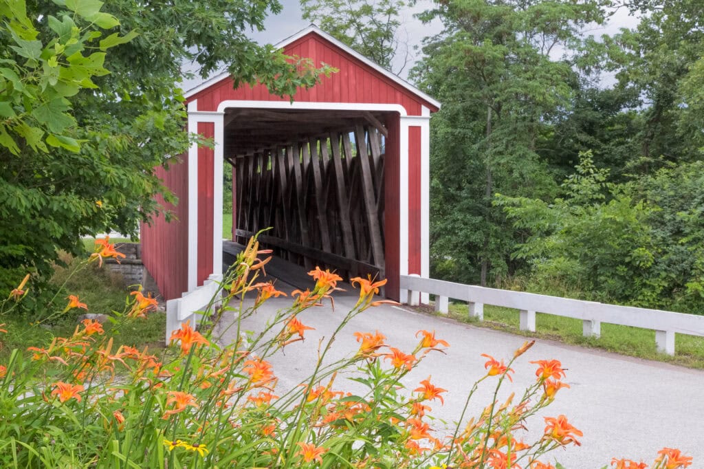 A red covered bridge surrounded by orange flowers in the small-town of Franklin, Indiana.